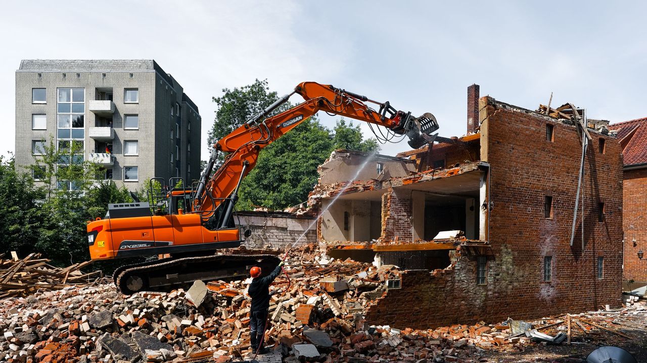 Pelle de démolition déconstruisant un bâtiment, gravats au sol